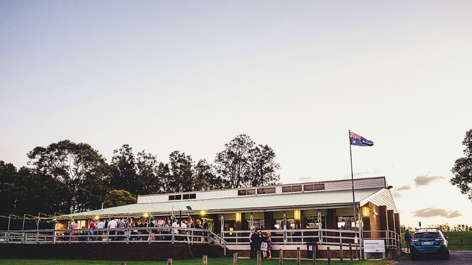 Wedding party on the deck at Kyla Hall at twilight - photo credit: @cloudfaceweddingphotography to by  banner image