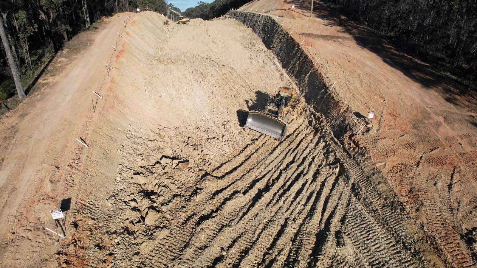 Image A large bulldozer cuts across a large earthworks cutting.
