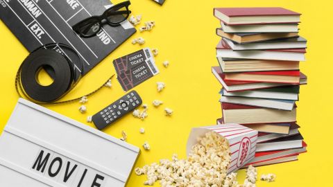 Image of a movie reel, tv remote, movie tickets and books on a yellow background.