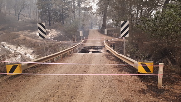 Image The bridge is completely burnt leaving a gapping hole in the road.