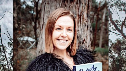 A smiling woman standing in front of a tree. 