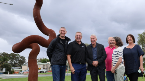 A group of people in front of a sculpture 