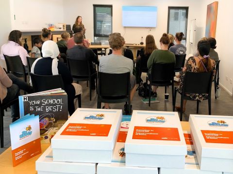 People watching a presenter, books in the foreground.