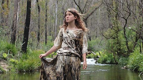 Image of young girl wearing a botanical printed dress, standing in water.