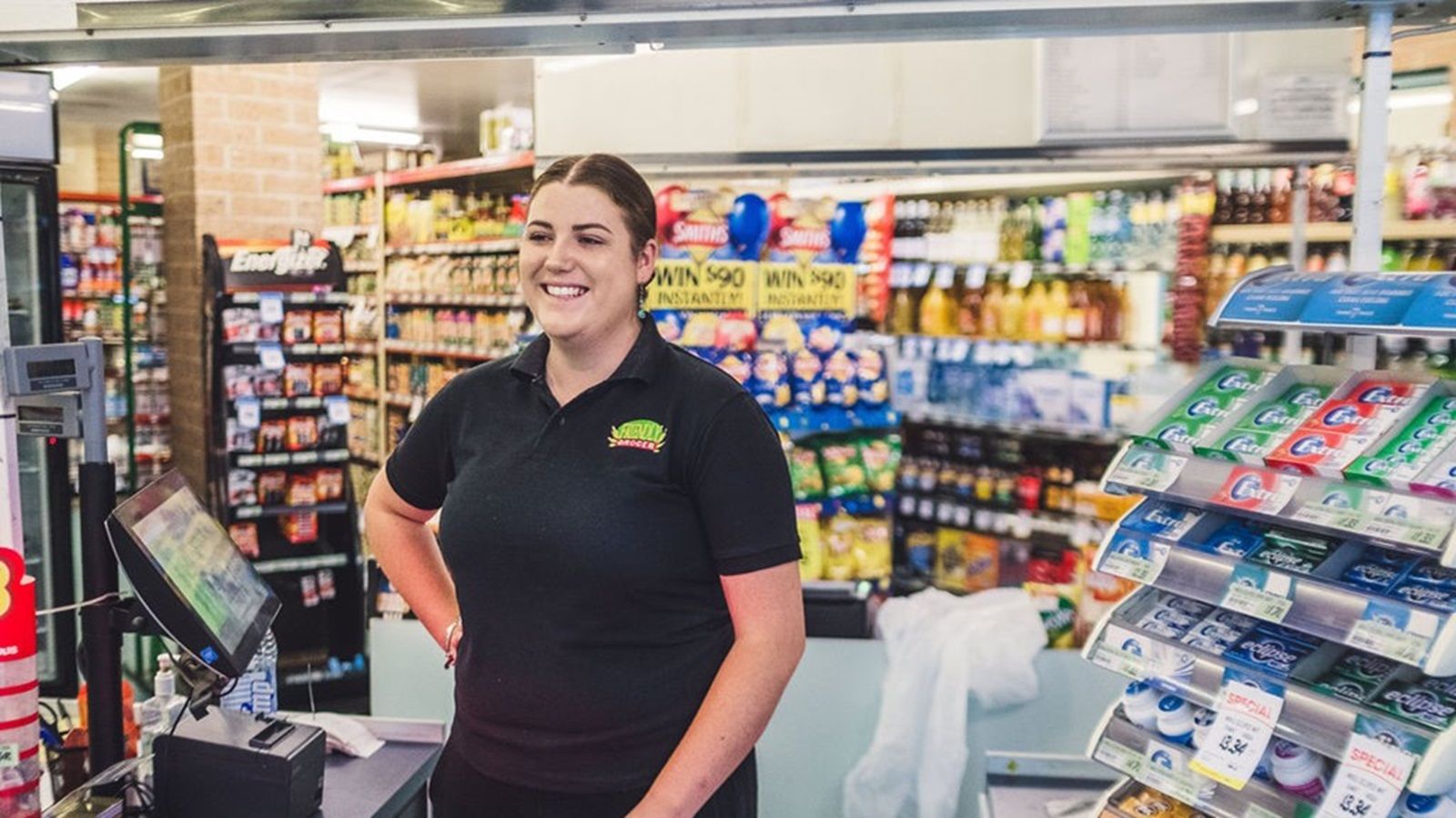 A grocer standing in front of Tuross Head supermarket shelves. banner image