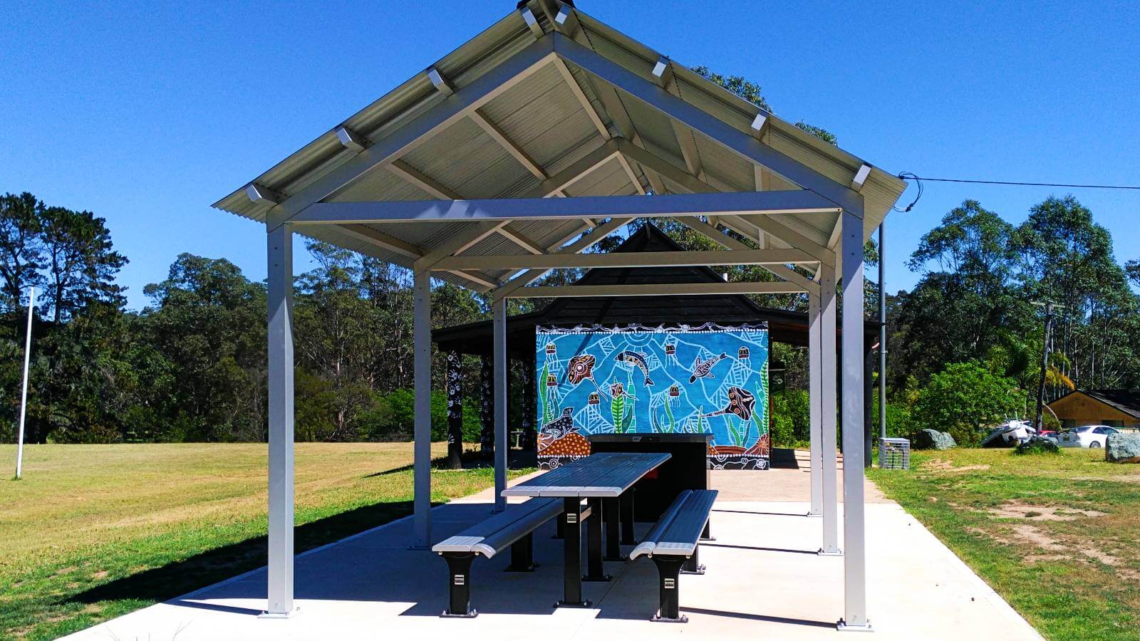 Image The large picnic shelter at Mogo playground with mural by local Aboriginal artist Bronwen Smith on the amenities block in the background  