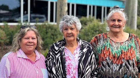Three indigenous women standing in front of council garden