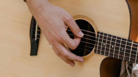 A hand strumming an acoustic guitar.