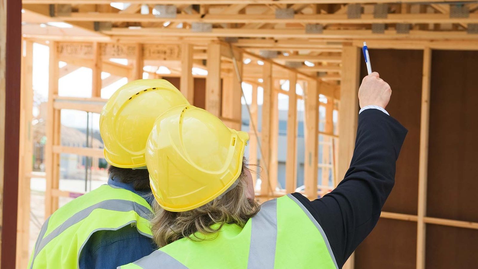 Two inspectors wearing yellow hard hats inspecting a house trusses banner image