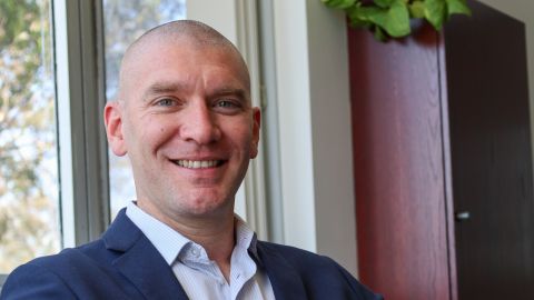 Mayor Mathew Hatcher smiling in front of a window