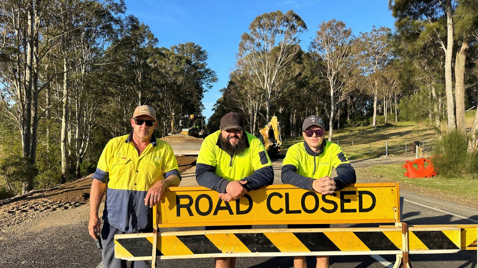 Image Workers stand behind a road closed sign 