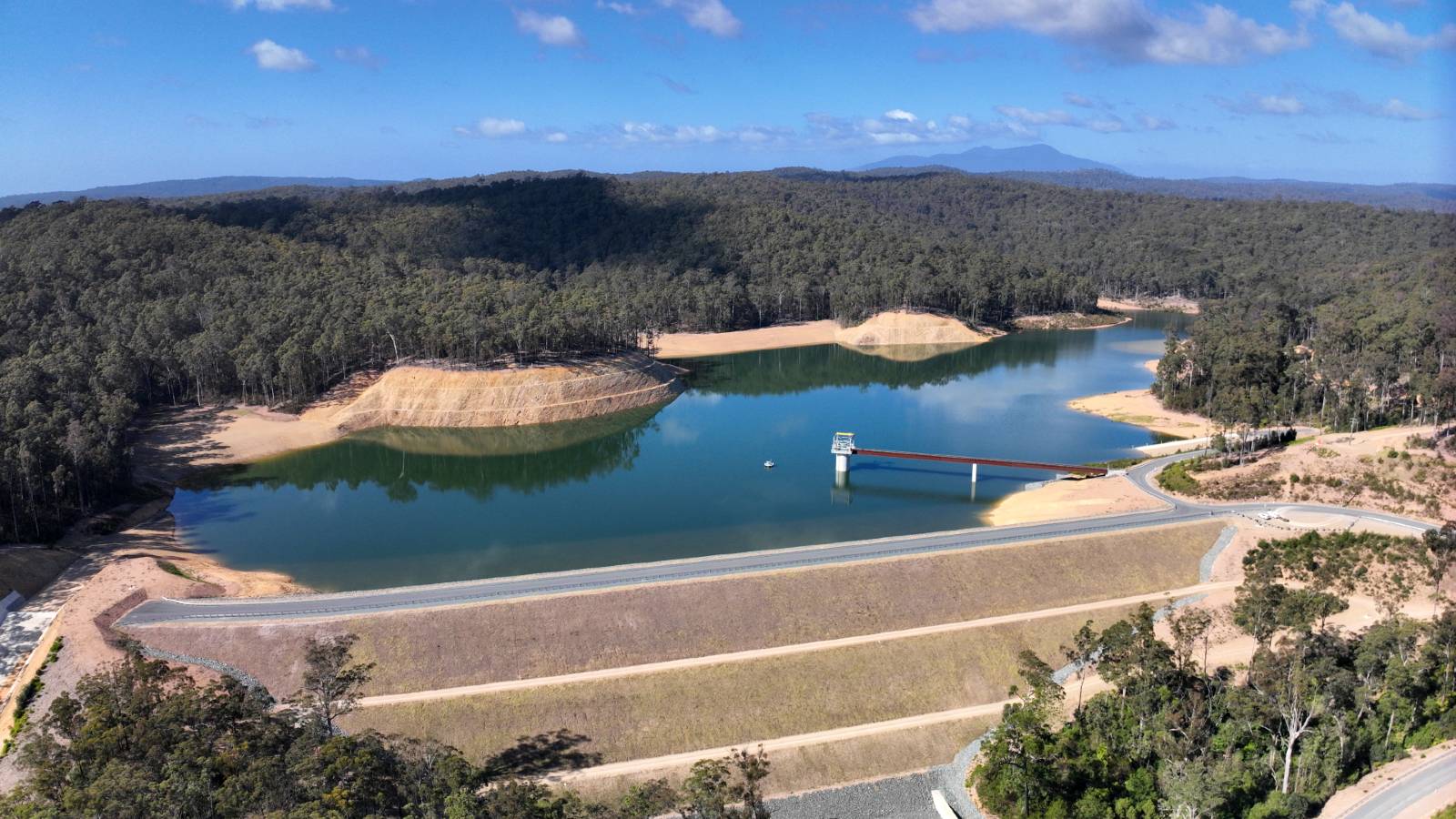 A large dam wall contains a water supply facility that is half full.