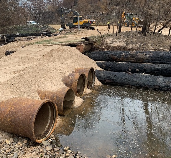 Image Large pipes and sand lay along the river bed providing temporary access. 