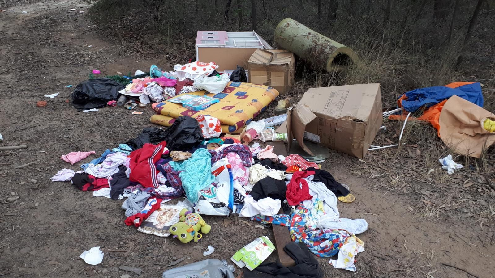 A pile of clothes and rubbish dumped in the bush banner image