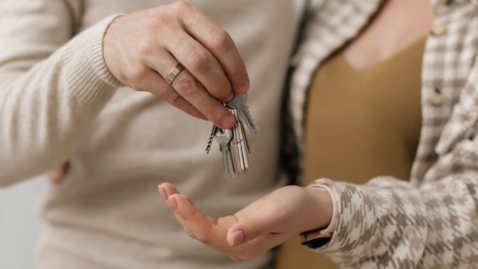 A woman and man's hands holding a house key banner image