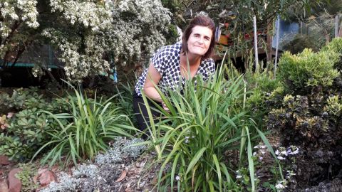 A woman crouches in a lovely native garden.
