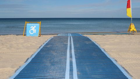 A mobility aid mat leading from beach sand to the water.