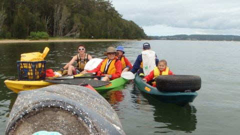 two kayaks with people collecting rubbish on the water 