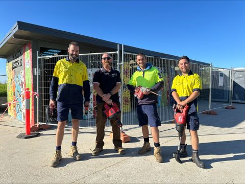 four men standing holding tools