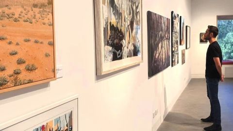 Man in black looking at painting on wall