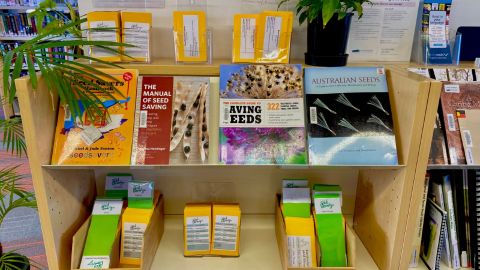 A bookshelf with packets of seeds and books on it