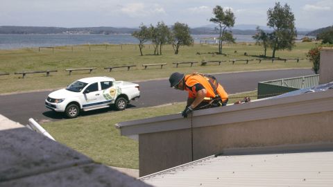 Man installing solar system on roof, beach in background