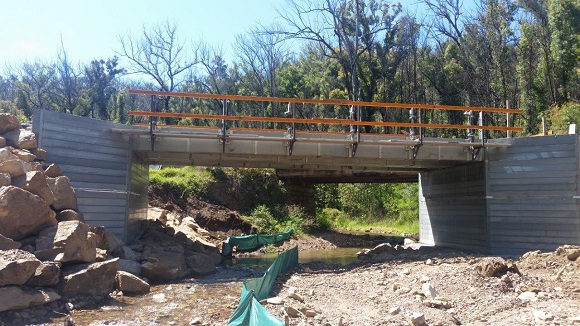 Image A bridge under construction straddles a creek