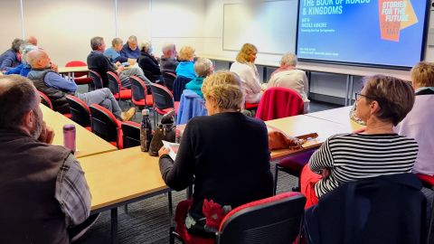 A group of people sitting at desks watching a big screen