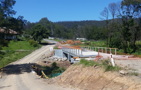 Image A bridge under construction sits alongside a dirt track