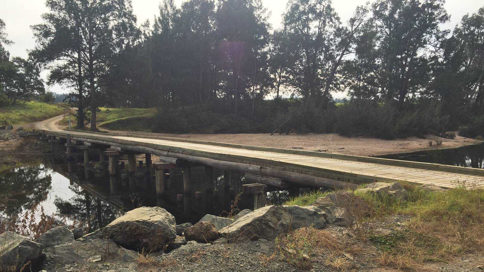 A long low timber bridge crosses a river