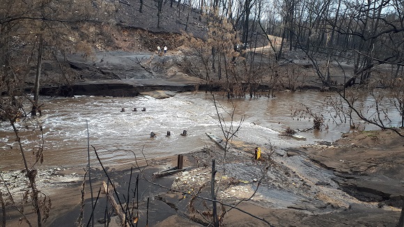 Image Flood water race down the creek where the bridge used to be