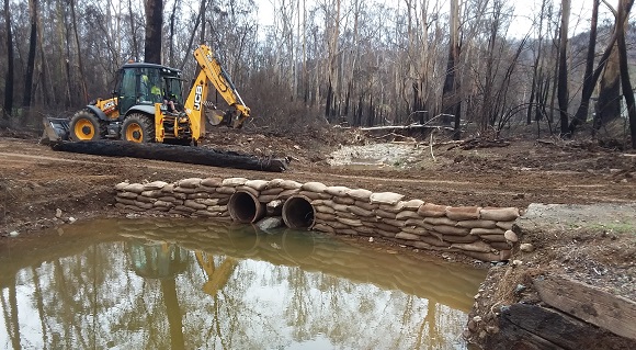 Image Pipes and sandbags help form a temporary track over muddy waters