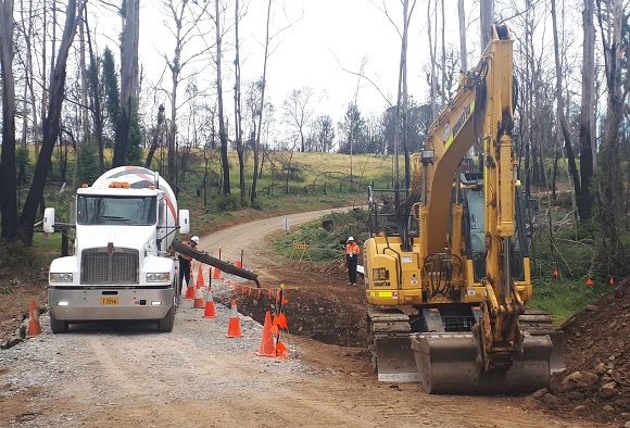 Image Concrete is being poured from a truck into a hole prepared by an excavator