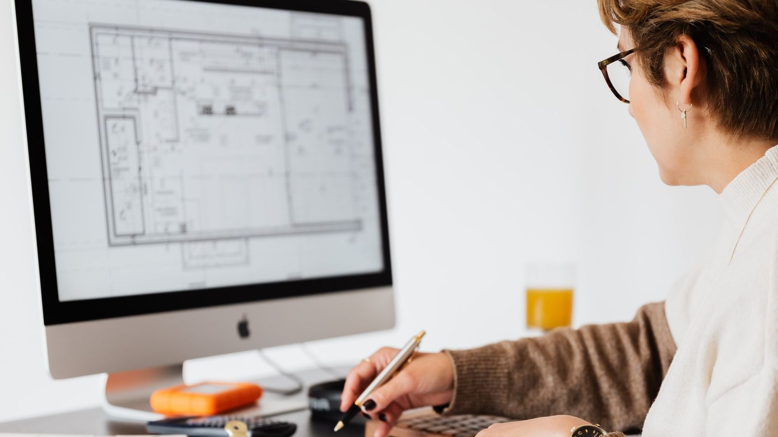 Woman looking at building plans on a computer screen banner image