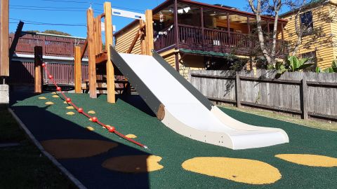 A slide and climbing rope on green flooring