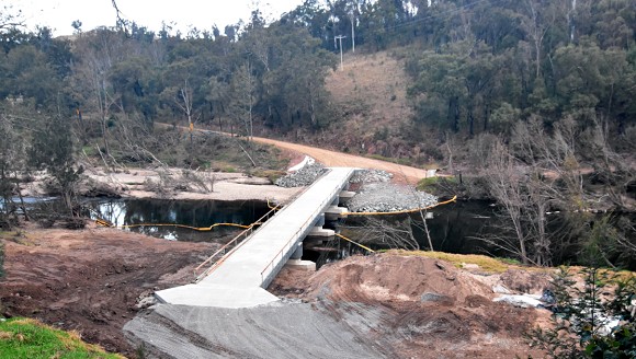 Image A long concrete bridge crosses a river in a rural setting