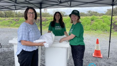 three people holding sheets