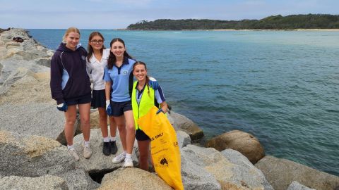 three teenagers standing on a breakwall with ocean in background