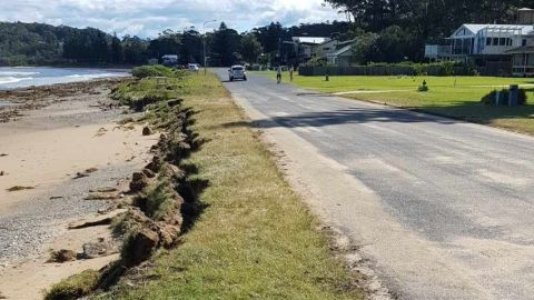 a road runs alongside a beach - the shore has receded very close to the road.