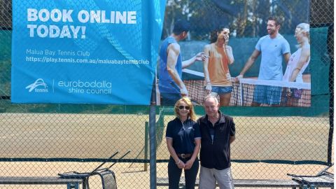 Female and male standing at a tennis court 