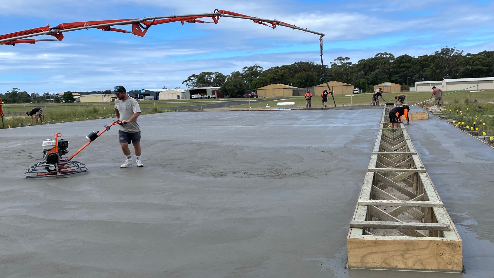 Image A person using machinery to smooth a concrete slab.