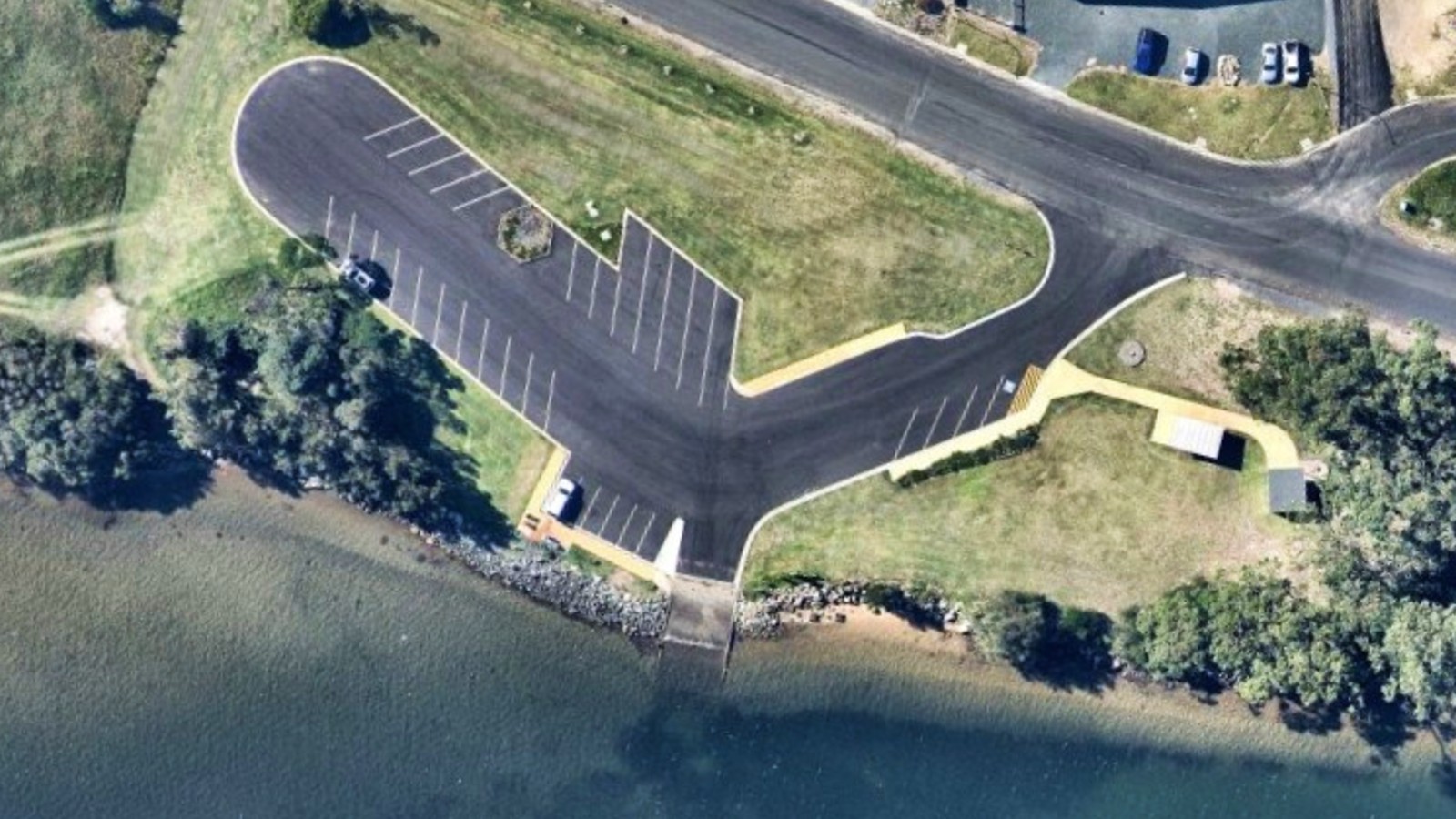 Image An aerial image shows a sealed car park with a boat ramp leading to a river