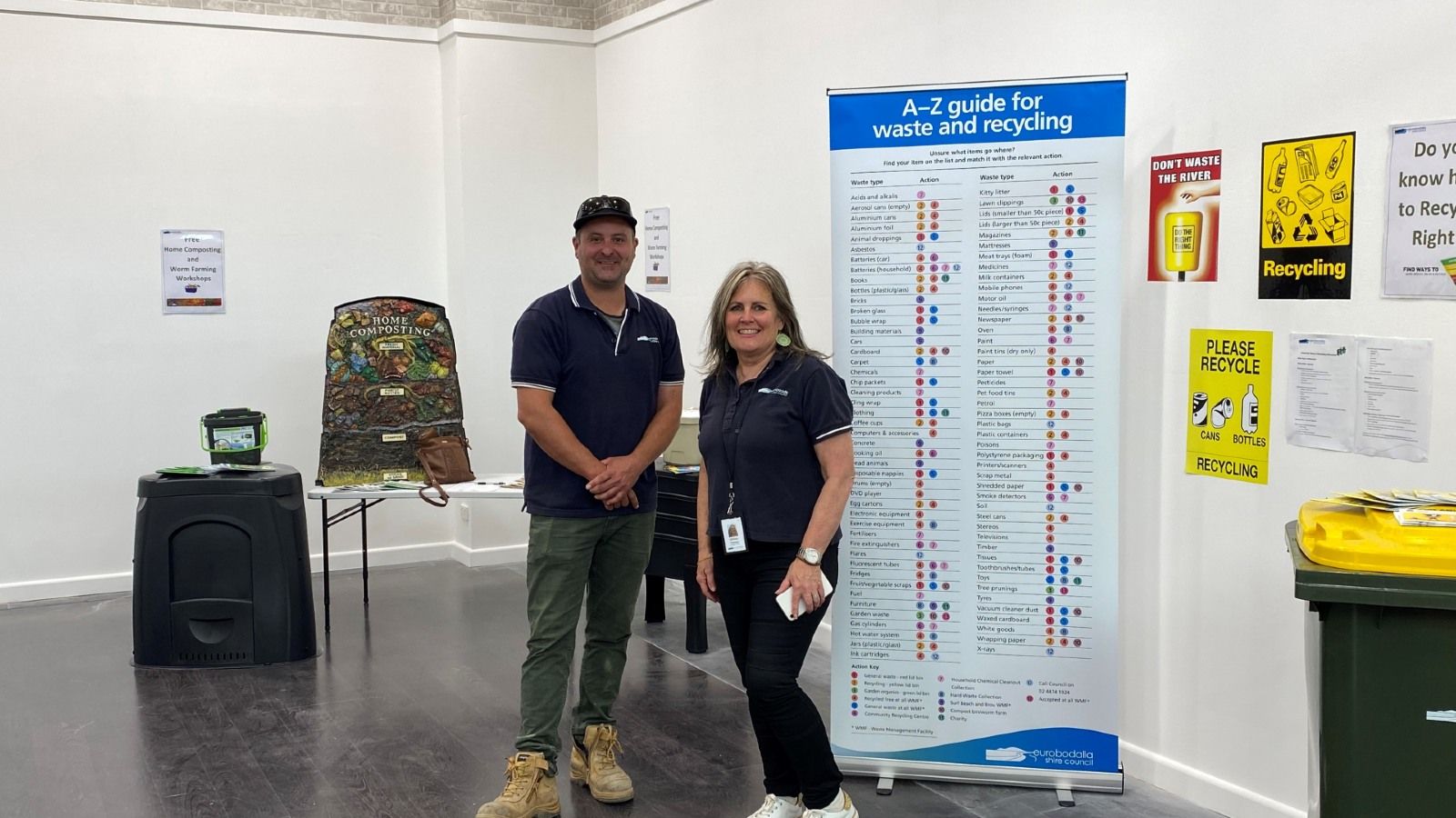 Two people standing in front of a recycling sign and next to a recycling bin banner image