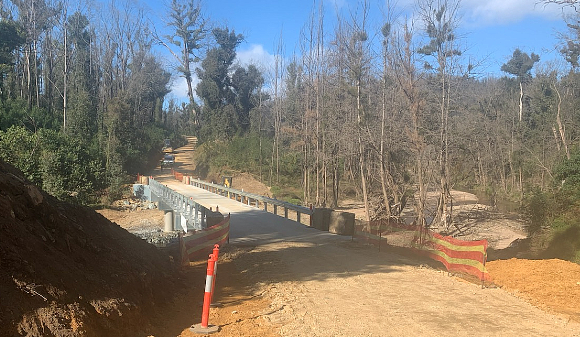 Image Guardrail lines a concrete bridge on a dirt road.