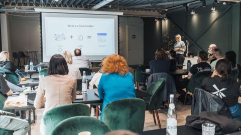 A woman presenting to a small room of adult participants.